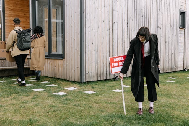 person placing a house for rent sign in front of house