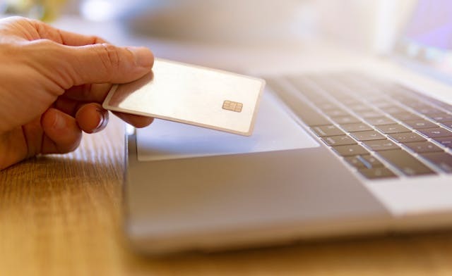 person holding a card over a laptop