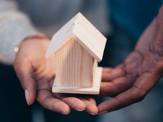 person holding a wooden figure of a house